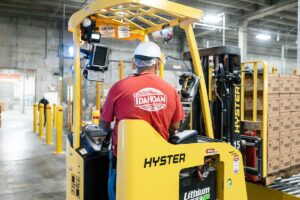 An Idahoan worker driving a forklift in a production warehouse setting